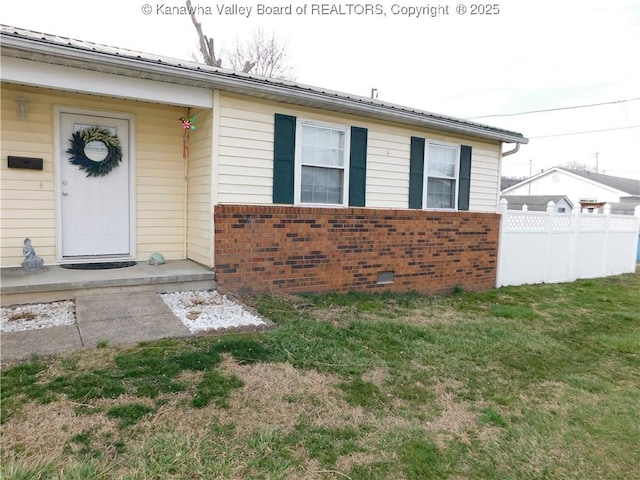 exterior space featuring fence, a yard, crawl space, brick siding, and metal roof