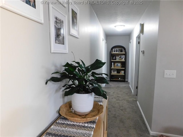 hall featuring baseboards and carpet