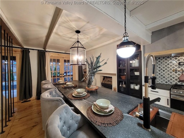 dining space with wood finished floors, beamed ceiling, and french doors