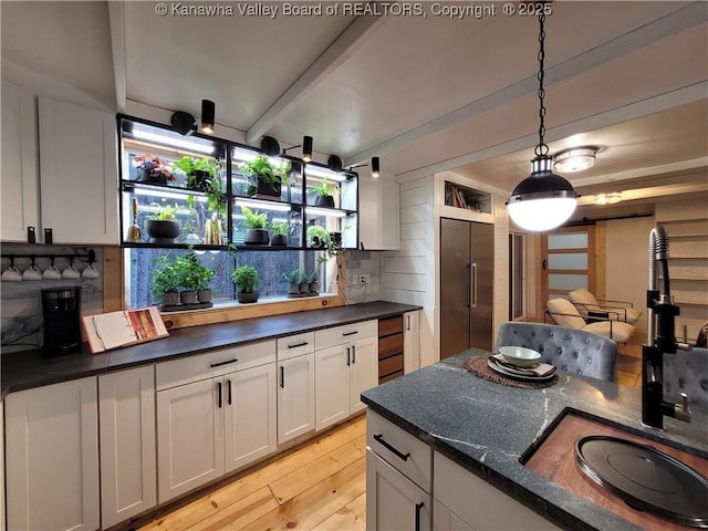 kitchen featuring tasteful backsplash, high end refrigerator, light wood-style flooring, hanging light fixtures, and white cabinetry