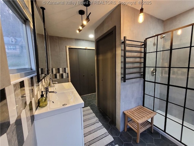 full bathroom with tile patterned flooring, tile walls, vanity, and tiled shower