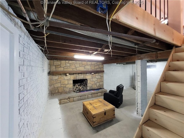 unfinished basement featuring stairway and a stone fireplace