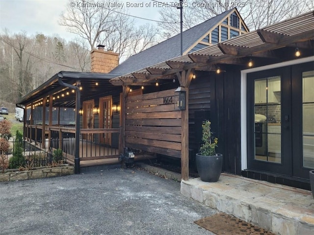 exterior space featuring french doors, a chimney, and a pergola