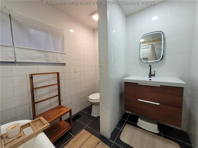 bathroom featuring tile patterned flooring, tile walls, toilet, and vanity