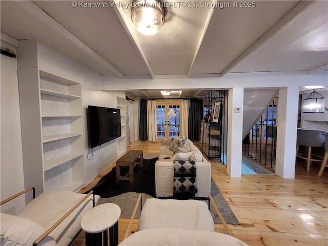 living room with hardwood / wood-style floors, beam ceiling, stairway, and french doors