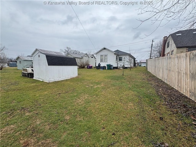 view of yard with a storage shed, an outbuilding, and fence