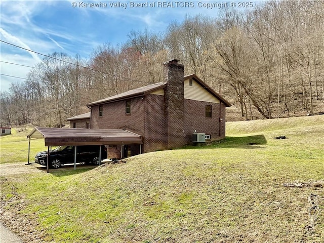 view of side of property featuring brick siding, a chimney, central AC, and a yard