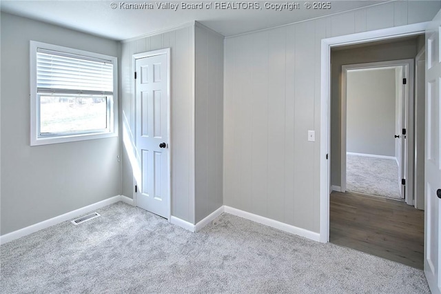 unfurnished bedroom with a closet, visible vents, baseboards, and carpet floors