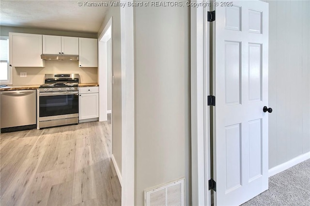 kitchen with under cabinet range hood, white cabinets, visible vents, and appliances with stainless steel finishes