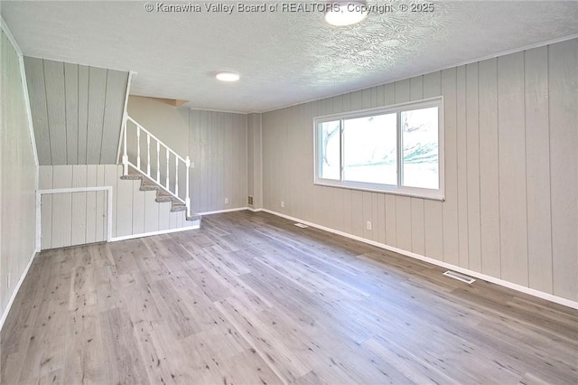 unfurnished room featuring stairway, baseboards, visible vents, and wood finished floors