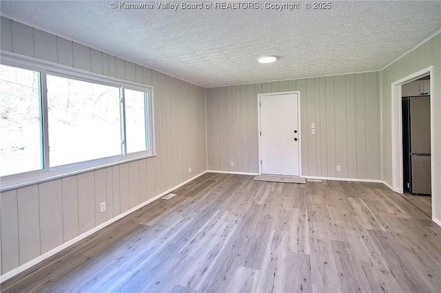 unfurnished room with visible vents, a textured ceiling, baseboards, and wood finished floors