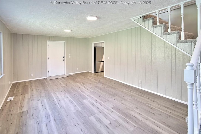 unfurnished living room with stairway, wood finished floors, and baseboards