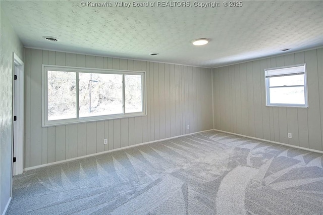 carpeted empty room featuring a textured ceiling and baseboards