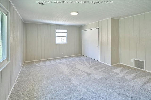 unfurnished bedroom with a closet, visible vents, ornamental molding, and carpet floors