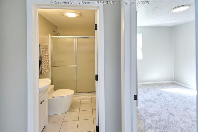 bathroom with tile patterned flooring, toilet, vanity, a stall shower, and a textured ceiling