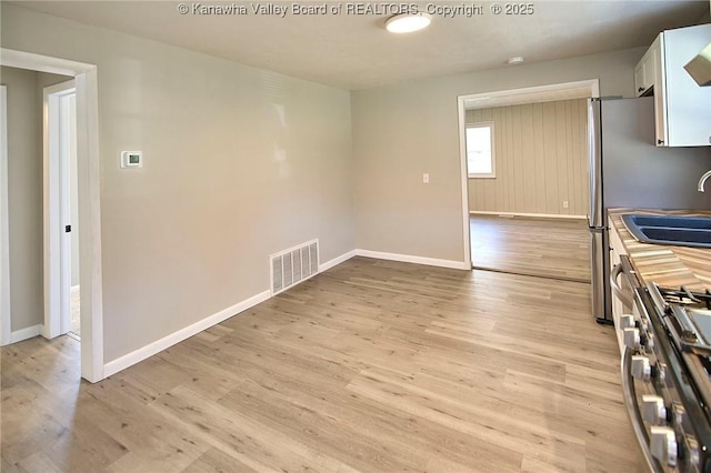 kitchen featuring baseboards, visible vents, stainless steel gas range, and light wood-type flooring