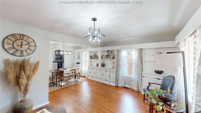 interior space featuring light wood finished floors, a notable chandelier, and built in shelves