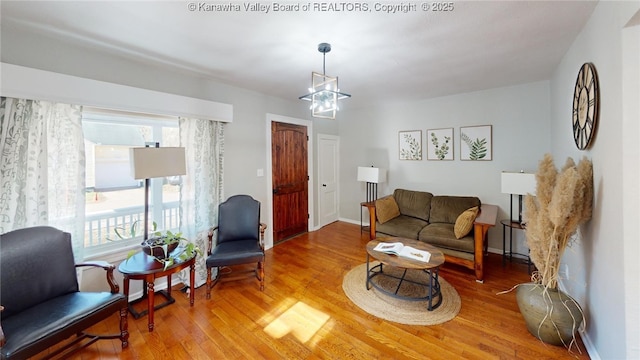 living room with baseboards, an inviting chandelier, and wood finished floors