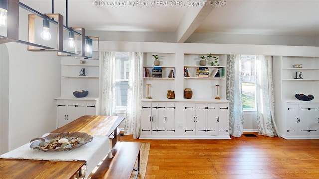 interior space featuring built in features, beamed ceiling, and light wood-style flooring