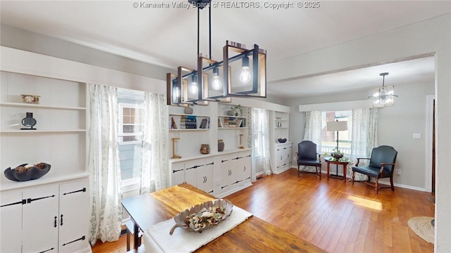 dining room with an inviting chandelier, built in shelves, baseboards, and light wood-type flooring