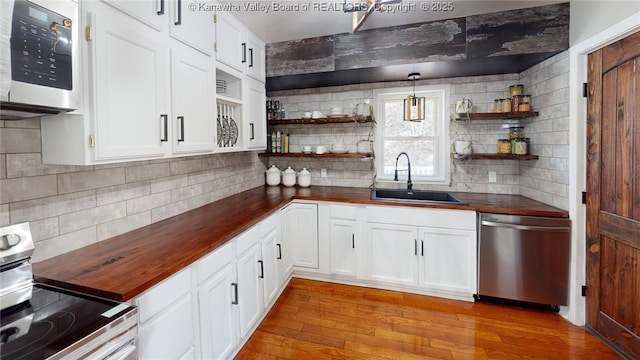 kitchen featuring open shelves, butcher block countertops, light wood-type flooring, appliances with stainless steel finishes, and a sink