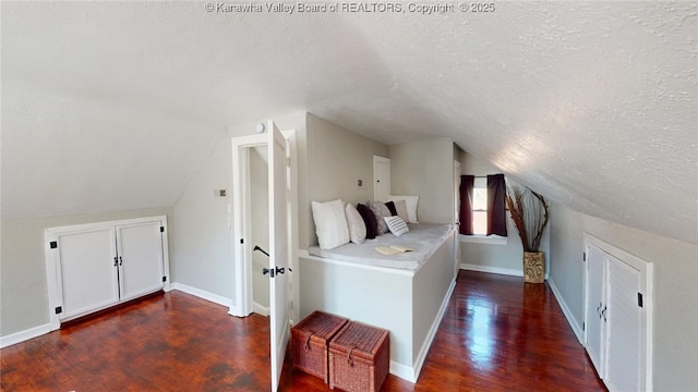 bedroom featuring baseboards, a textured ceiling, wood finished floors, and vaulted ceiling