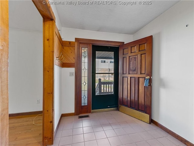 entryway with baseboards, visible vents, and a textured ceiling