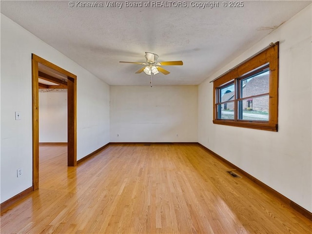 unfurnished room with baseboards, visible vents, light wood finished floors, ceiling fan, and a textured ceiling