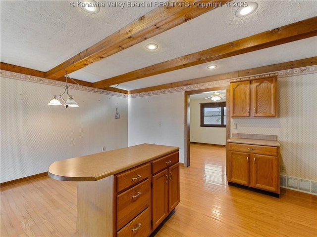 kitchen featuring visible vents, wallpapered walls, beamed ceiling, light wood-style floors, and a textured ceiling