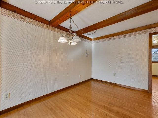 empty room featuring baseboards, wallpapered walls, beam ceiling, light wood-type flooring, and a chandelier