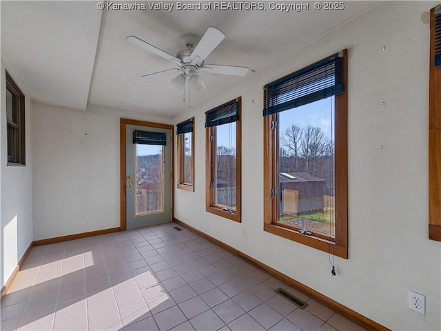 tiled empty room with a ceiling fan, visible vents, and baseboards