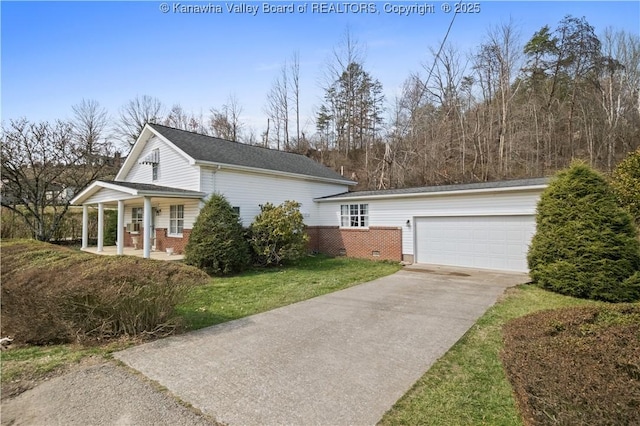 view of side of home featuring a yard, brick siding, a porch, and driveway