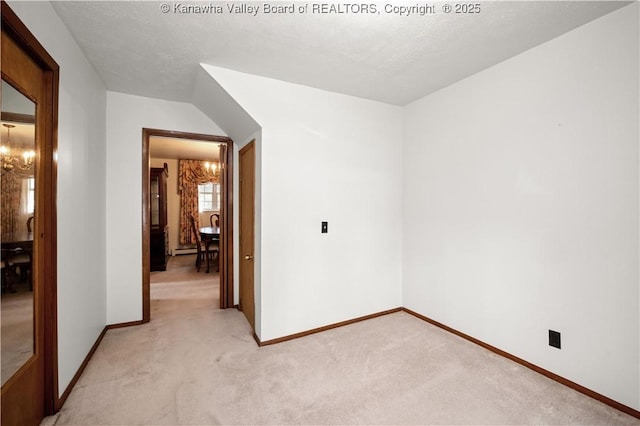empty room with a textured ceiling, baseboards, a chandelier, and light carpet