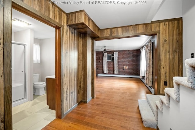corridor with stairway, wooden walls, and light wood finished floors