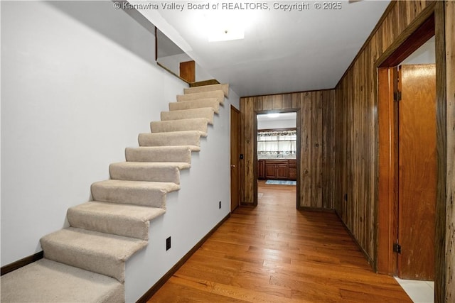 stairs featuring wooden walls, baseboards, and wood finished floors