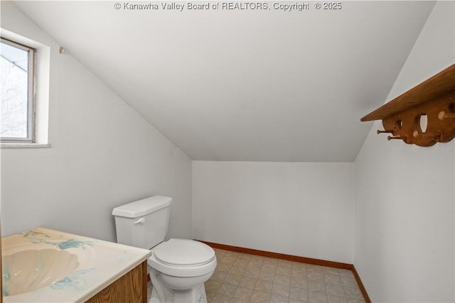 half bathroom featuring tile patterned floors, baseboards, toilet, and vaulted ceiling