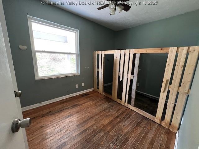 unfurnished bedroom featuring wood finished floors, baseboards, and ceiling fan