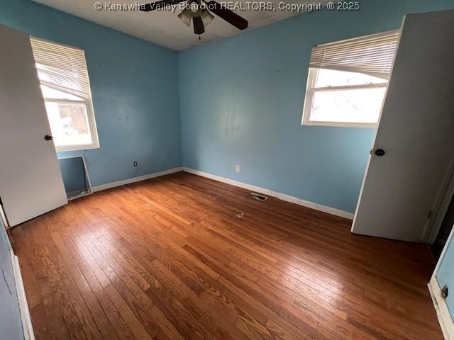 spare room with hardwood / wood-style floors, plenty of natural light, baseboards, and ceiling fan