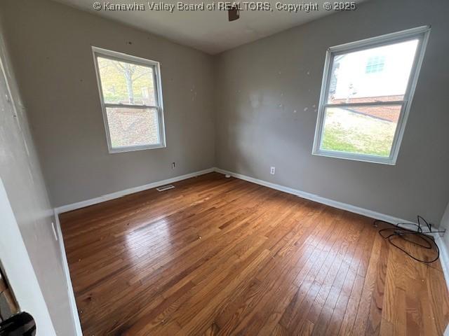 empty room featuring hardwood / wood-style flooring, plenty of natural light, a ceiling fan, and baseboards