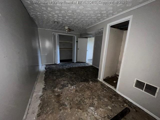 corridor with visible vents, a textured ceiling, and ornamental molding