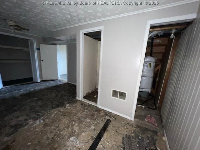 interior space featuring visible vents, multiple closets, a textured ceiling, and crown molding