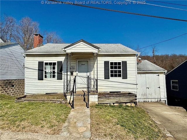 bungalow-style home with a chimney, roof with shingles, and a front yard