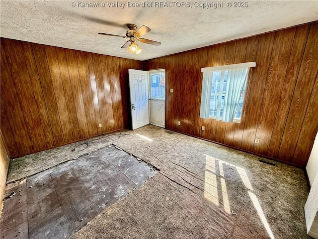 empty room featuring visible vents, a textured ceiling, and a ceiling fan