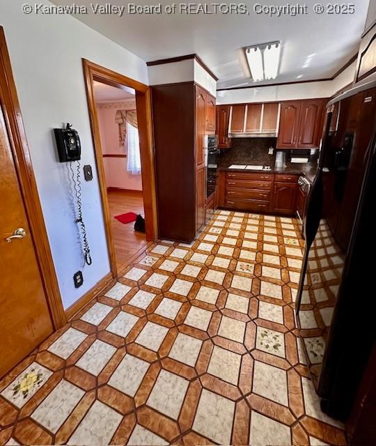 kitchen with brown cabinets, tasteful backsplash, dark countertops, cooktop, and baseboards