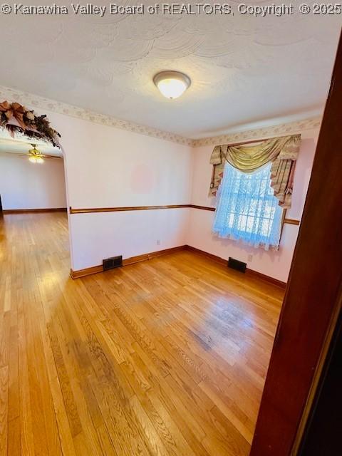 unfurnished room featuring visible vents, baseboards, and wood finished floors