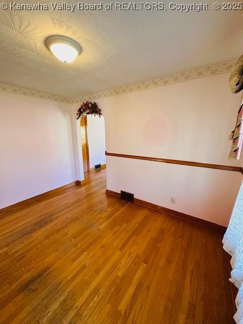 empty room featuring baseboards, a textured ceiling, and wood finished floors