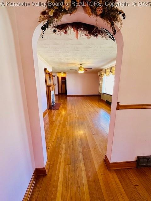 hallway featuring baseboards, arched walkways, visible vents, and hardwood / wood-style floors