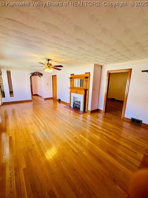 unfurnished living room with visible vents, baseboards, ceiling fan, wood finished floors, and a textured ceiling