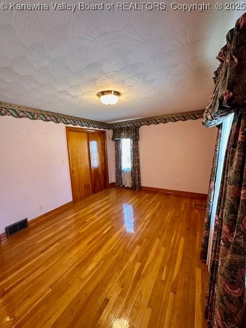 spare room featuring baseboards, visible vents, and light wood finished floors