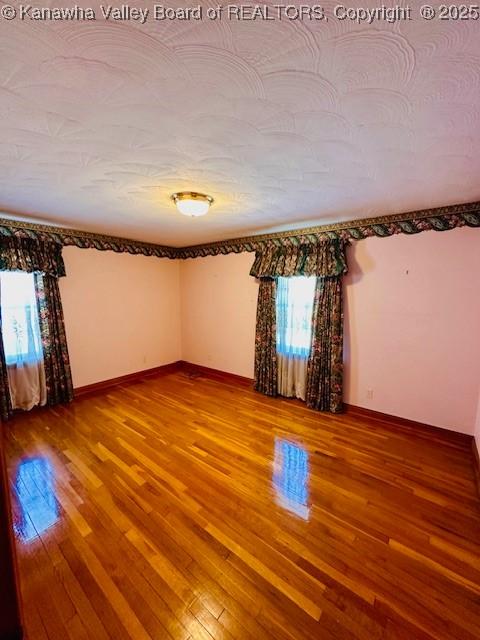 unfurnished room with baseboards and wood-type flooring